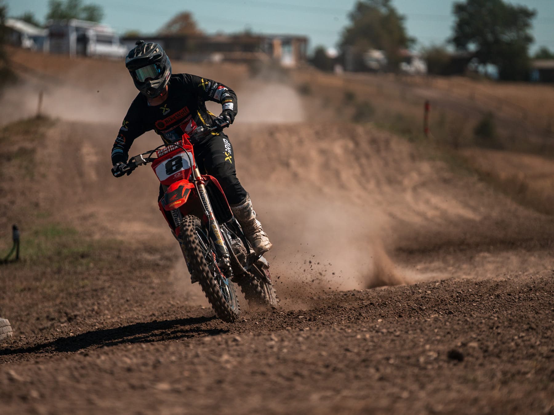 Motocross-Fahrer frontal im Anlieger, Erde fliegt hinter dem Hinterrad