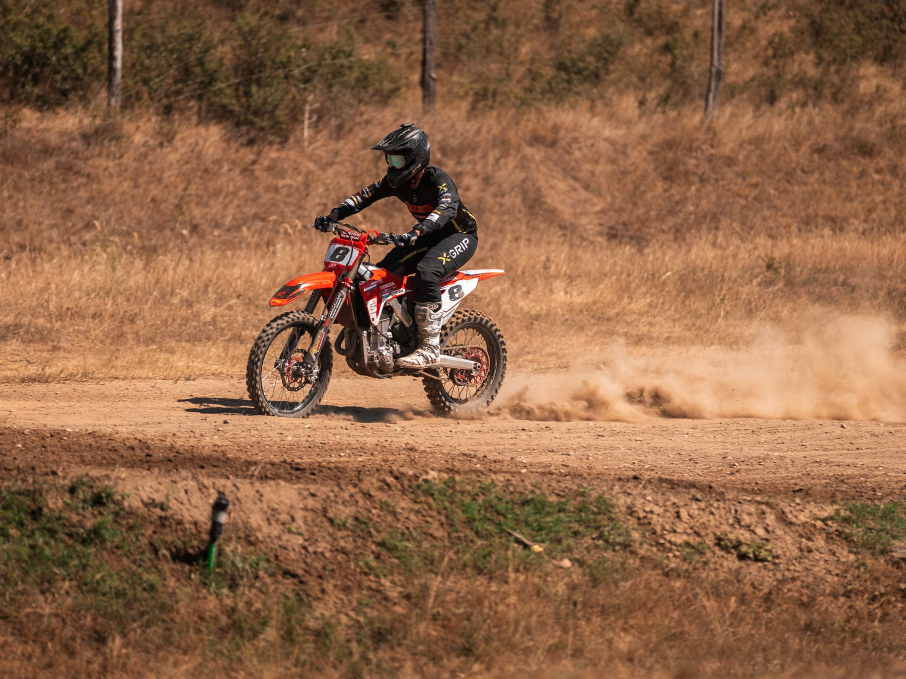 Enduro-Fahrer auf der weiten Cross-Country-Piste mit aufgewirbelter Staubfahne
