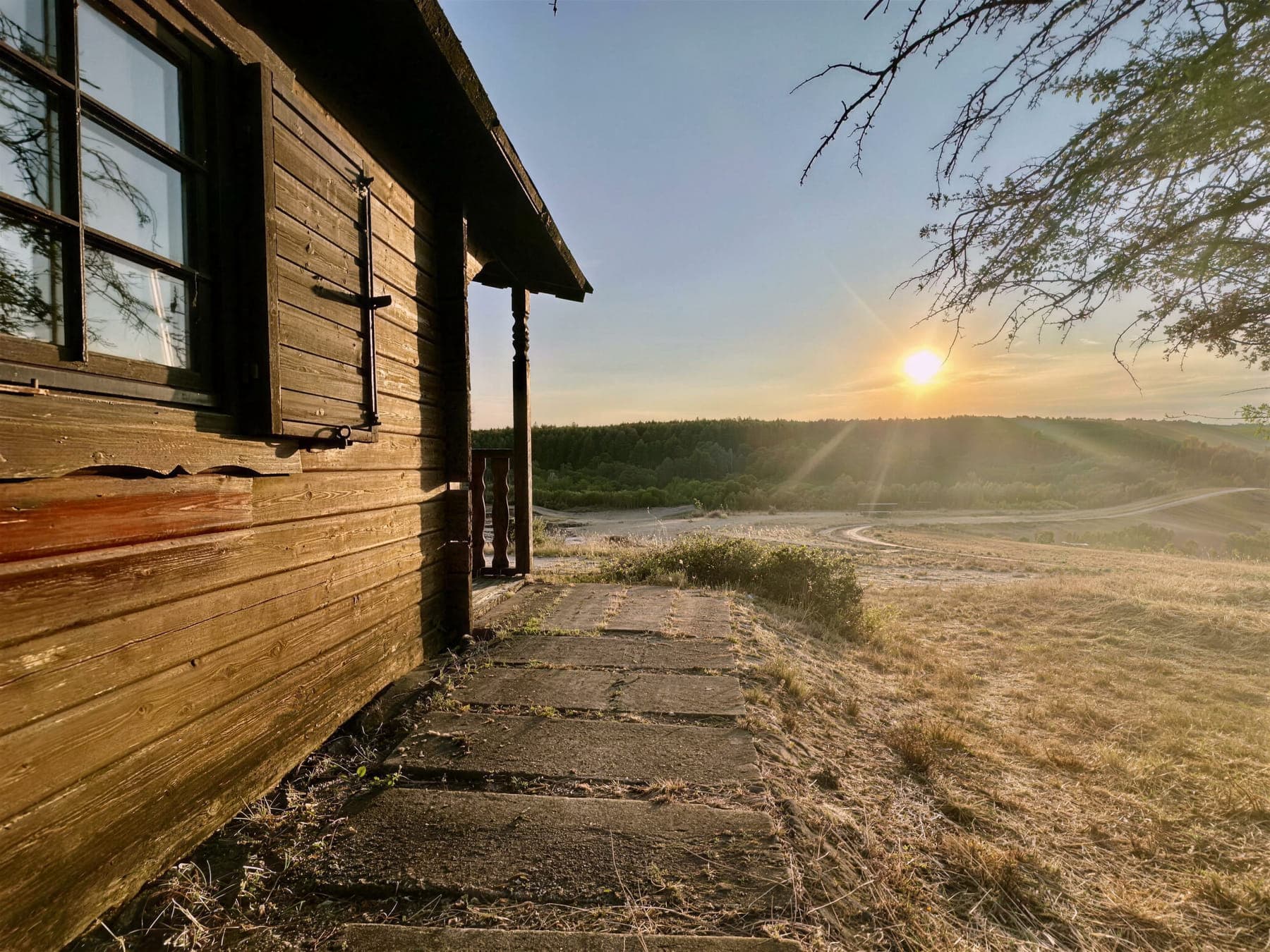 Holzhütte am Hang mit Blick über das Gelände bei Sonnenuntergang